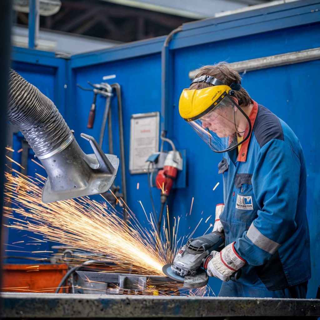 Worthington Lehrling bei der Arbeit in der Werkstatt beim Arbeiten mit dem Winkelschleifer